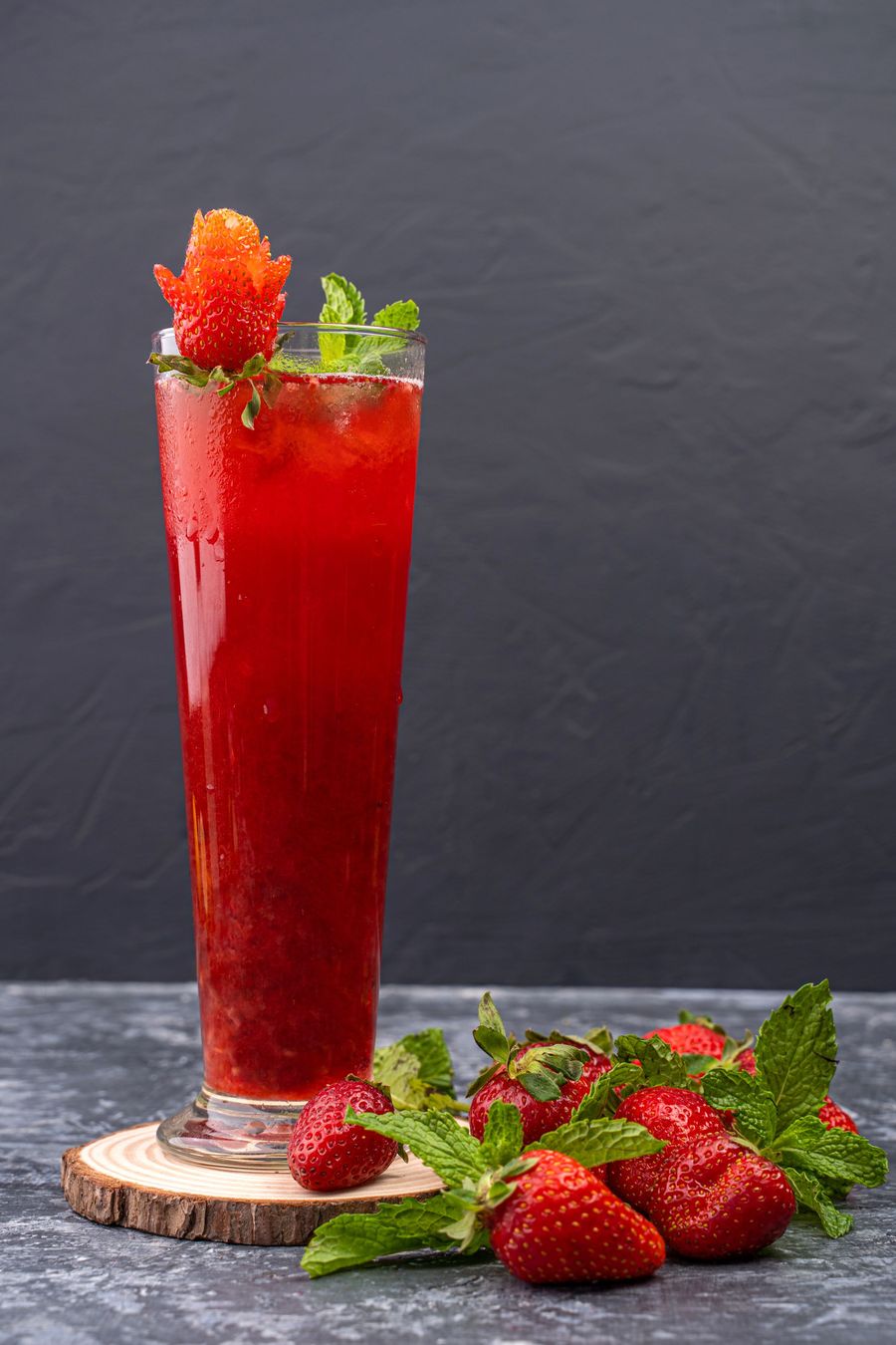 Strawberry mocktail in a tall glass with fresh strawberries and mint